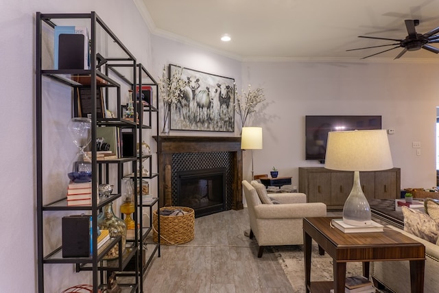 living room featuring a tiled fireplace, ceiling fan, light hardwood / wood-style floors, and ornamental molding