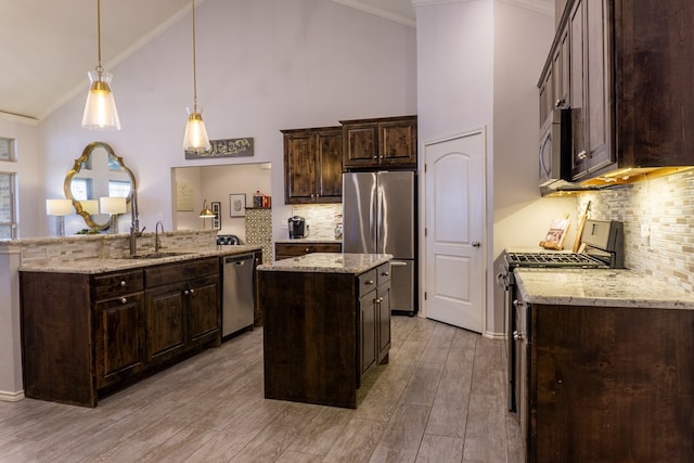 kitchen featuring sink, a center island, kitchen peninsula, light hardwood / wood-style floors, and appliances with stainless steel finishes