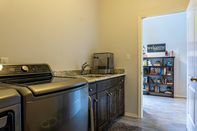 laundry room featuring light hardwood / wood-style floors, cabinets, and sink