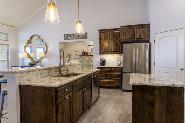 kitchen with a kitchen breakfast bar, an island with sink, ornamental molding, and appliances with stainless steel finishes