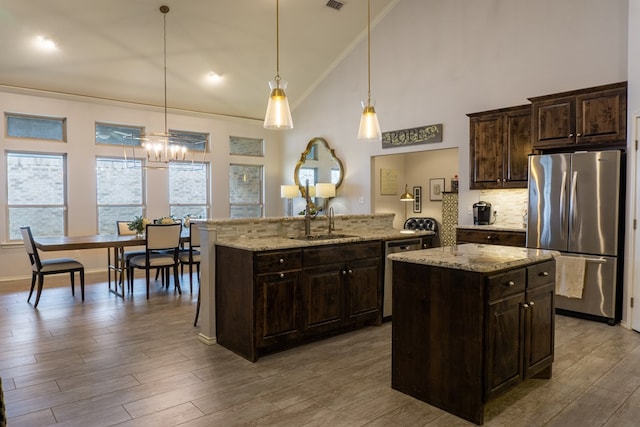 kitchen with stainless steel appliances, crown molding, sink, pendant lighting, and an island with sink