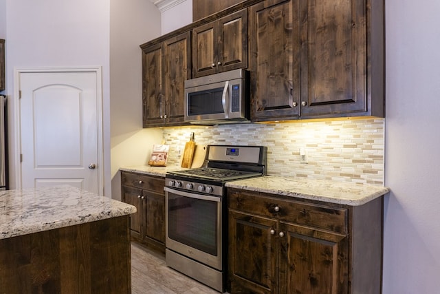 kitchen featuring light stone countertops, dark brown cabinets, and appliances with stainless steel finishes