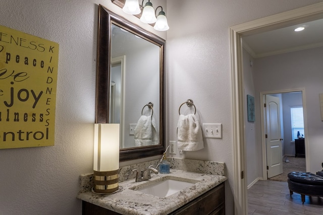 bathroom featuring vanity, wood-type flooring, and ornamental molding