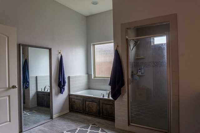 bathroom featuring a healthy amount of sunlight, wood-type flooring, and shower with separate bathtub