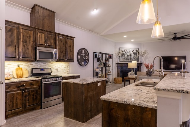 kitchen with hanging light fixtures, lofted ceiling, a kitchen island with sink, dark brown cabinets, and appliances with stainless steel finishes