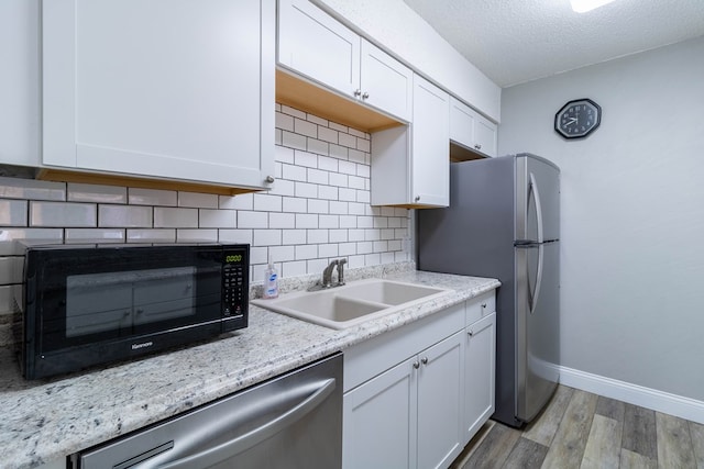 kitchen with sink, light wood-type flooring, a textured ceiling, white cabinetry, and stainless steel appliances