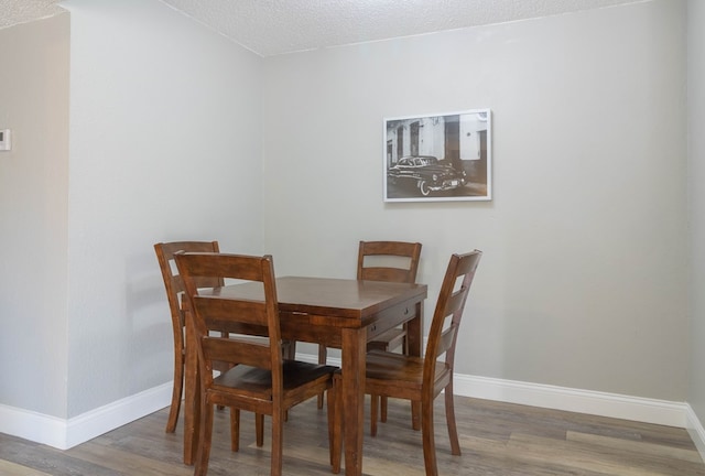 dining space with hardwood / wood-style floors and a textured ceiling