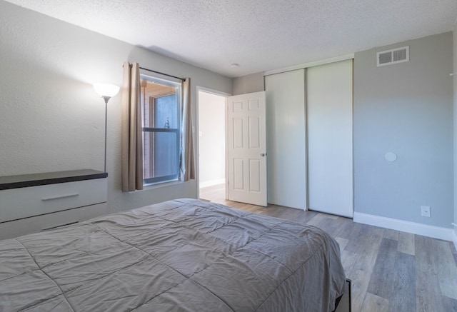 unfurnished bedroom with hardwood / wood-style floors, a textured ceiling, and a closet