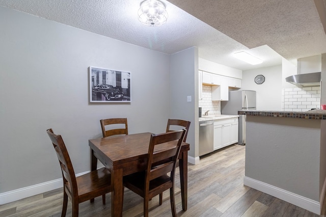 dining area featuring a textured ceiling and light wood-type flooring