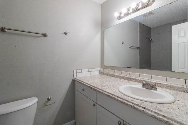 bathroom featuring decorative backsplash, vanity, a textured ceiling, and toilet