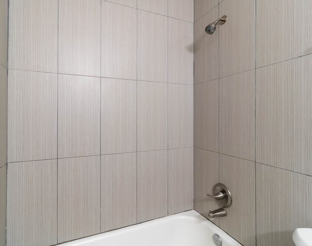 bathroom featuring tiled shower / bath combo and toilet