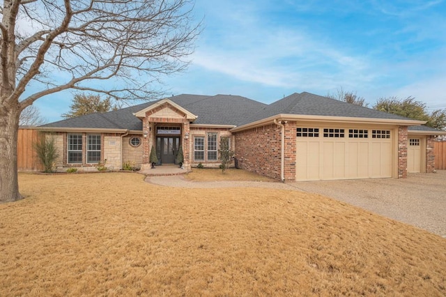 1900 Fringewood Dr, Midland, TX 79707 - ranch-style home with a shingled roof, a front yard, gravel driveway, brick siding, and a garage