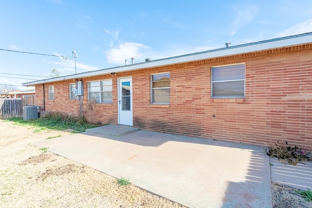 rear view of property featuring a patio area, cooling unit, and brick siding