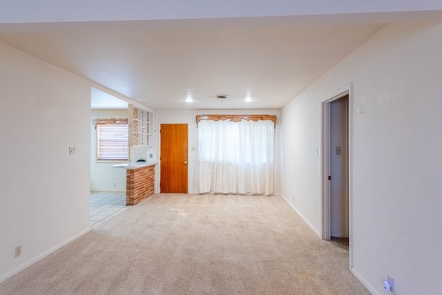 unfurnished room featuring baseboards and light carpet