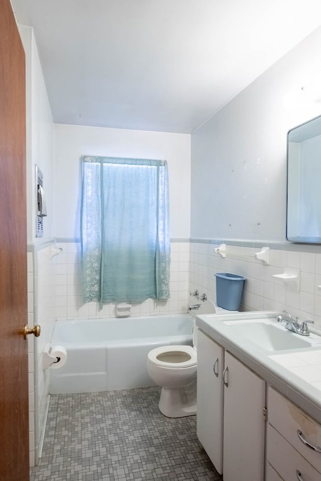 bathroom featuring vanity, tile walls, toilet, and a tub