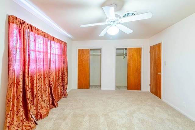 bedroom featuring baseboards, a ceiling fan, carpet, and multiple closets