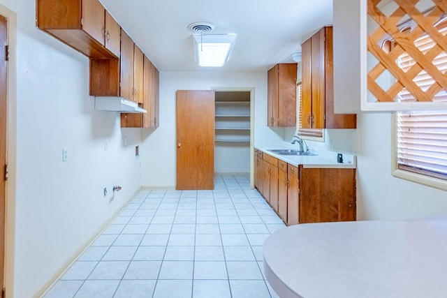 kitchen featuring light tile patterned flooring, visible vents, brown cabinets, and a sink