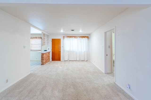 carpeted spare room featuring plenty of natural light and baseboards