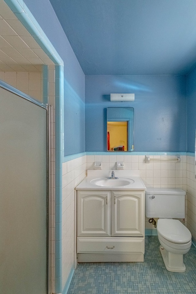 bathroom featuring tile walls, toilet, a stall shower, and wainscoting