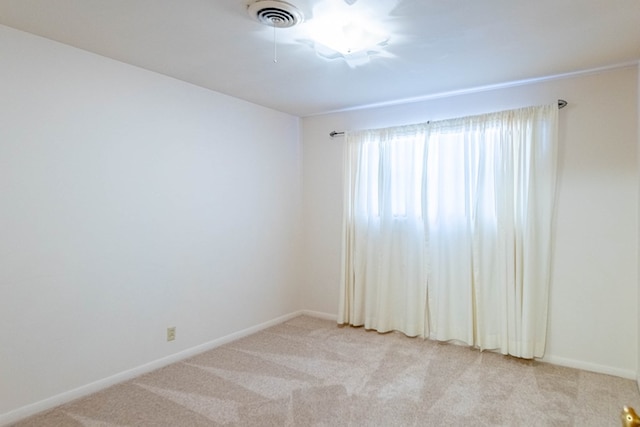 unfurnished room with visible vents, light colored carpet, and baseboards