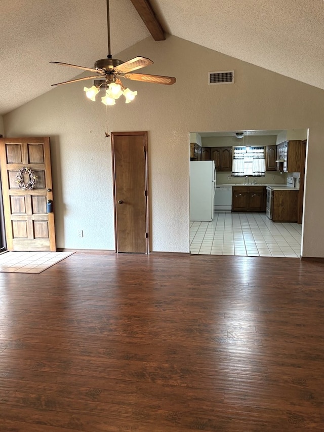 unfurnished living room with light wood-type flooring, visible vents, a ceiling fan, and vaulted ceiling with beams