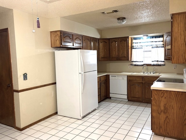 kitchen with visible vents, a sink, a textured ceiling, white appliances, and light countertops