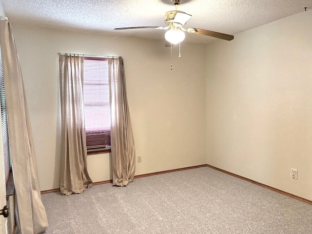 empty room featuring a textured ceiling, light carpet, baseboards, and ceiling fan