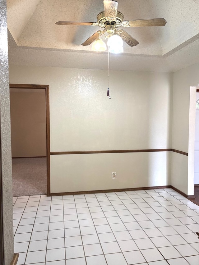 spare room with light tile patterned floors, baseboards, a textured ceiling, and a ceiling fan