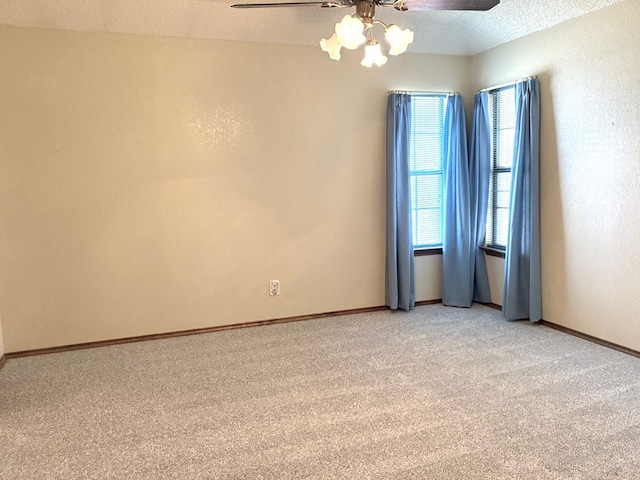 spare room featuring a textured ceiling, light colored carpet, baseboards, and ceiling fan