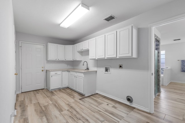 3502 Wedgewood St, Midland, TX 79707 - laundry area featuring washer hookup, hookup for an electric dryer, light wood-type flooring, and cabinet space