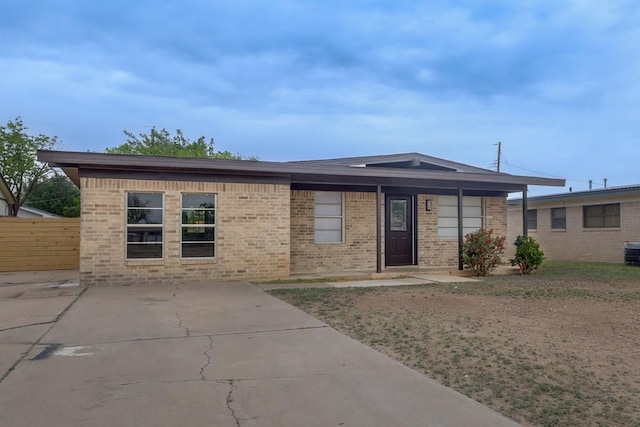 ranch-style home featuring brick siding and fence