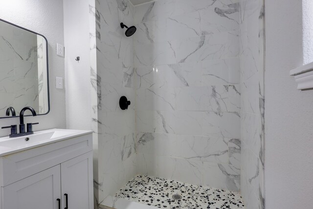 bathroom featuring vanity and a marble finish shower