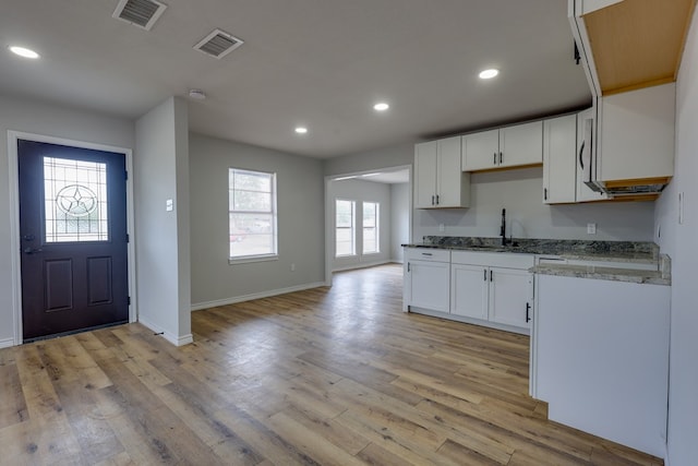 kitchen with light stone countertops, white cabinetry, baseboards, recessed lighting, and light wood-type flooring
