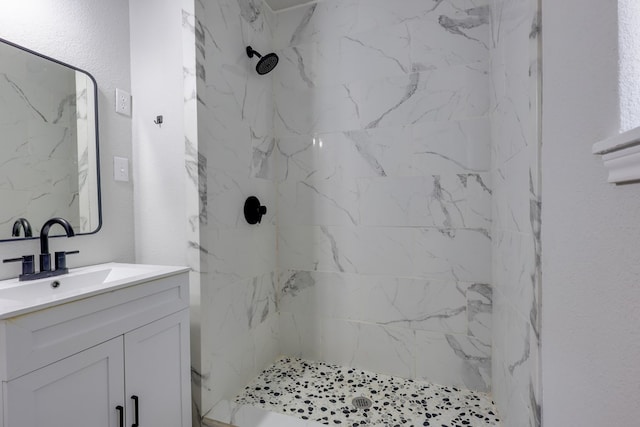 bathroom featuring vanity and a marble finish shower