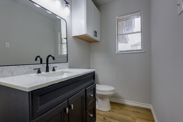 bathroom with toilet, wood finished floors, vanity, and baseboards
