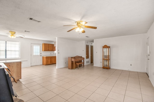 unfurnished living room featuring a textured ceiling, light tile patterned flooring, and ceiling fan