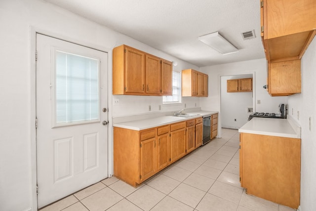 kitchen featuring sink, dishwasher, a textured ceiling, and light tile patterned floors