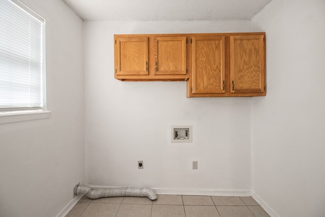 washroom with light tile patterned floors, a textured ceiling, hookup for a washing machine, cabinets, and electric dryer hookup