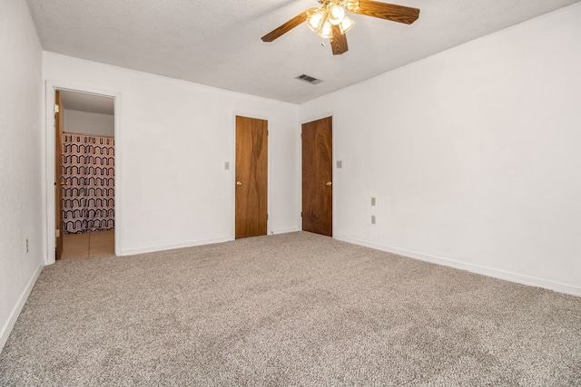 carpeted empty room with ceiling fan and a textured ceiling