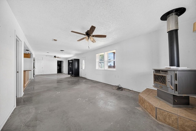 5408 E Loop 250e Unit A, Midland, TX 79705 - unfurnished living room with a wood stove, a ceiling fan, concrete flooring, and a textured ceiling