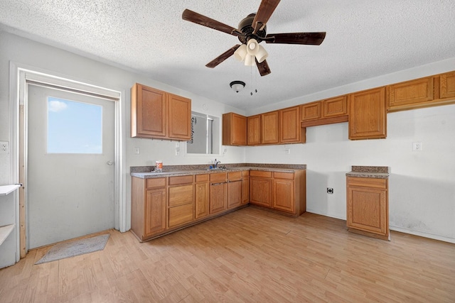 5408 E Loop 250e Unit A, Midland, TX 79705 - kitchen featuring light wood-style flooring, brown cabinetry, plenty of natural light, and a textured ceiling