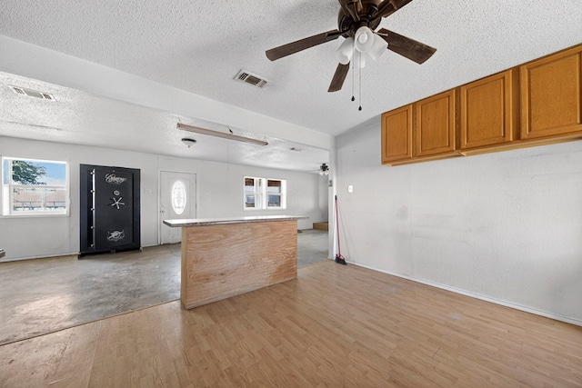5408 E Loop 250e Unit A, Midland, TX 79705 - kitchen with a ceiling fan, a textured ceiling, brown cabinets, open floor plan, and light wood finished floors