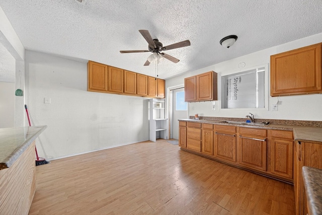 5408 E Loop 250e Unit A, Midland, TX 79705 - kitchen with a textured ceiling, ceiling fan, light wood finished floors, and brown cabinetry