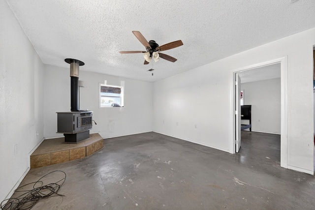5408 E Loop 250e Unit A, Midland, TX 79705 - unfurnished living room featuring concrete flooring, ceiling fan, a textured ceiling, and a wood stove