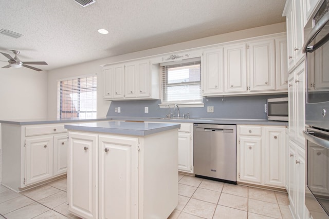 kitchen featuring ceiling fan, a center island, a textured ceiling, a sink, and stainless steel appliances