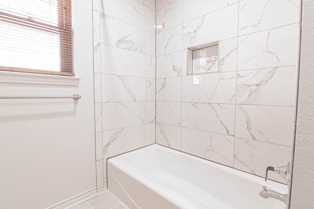 full bath featuring baseboards, washtub / shower combination, and tile patterned floors