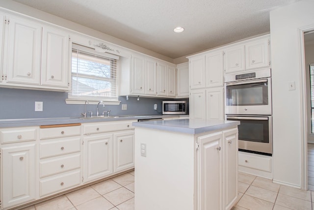 kitchen featuring a kitchen island, stainless steel appliances, white cabinetry, and light tile patterned flooring