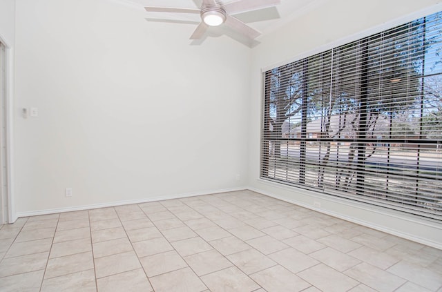 spare room with baseboards, a ceiling fan, and a wealth of natural light