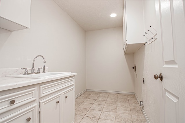 laundry area with cabinet space, a sink, a textured ceiling, baseboards, and hookup for an electric dryer