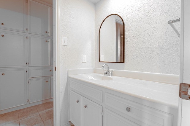 bathroom featuring tile patterned flooring, a textured wall, and vanity